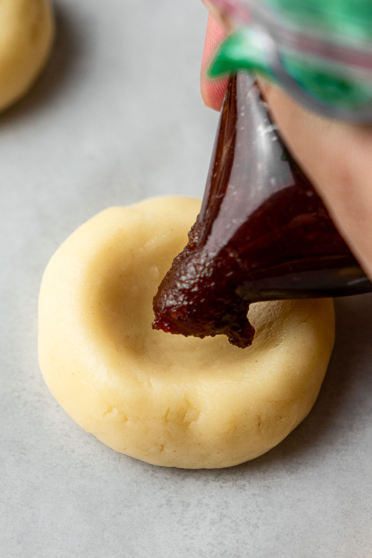 Piping guava paste into a cream cheese cookie with a thumbprint.