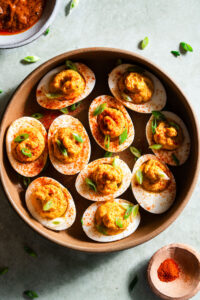 Achaari Deviled Eggs with scallions in a large bowl.