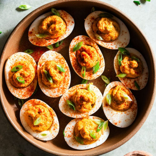 Achaari Deviled Eggs with scallions in a large bowl.