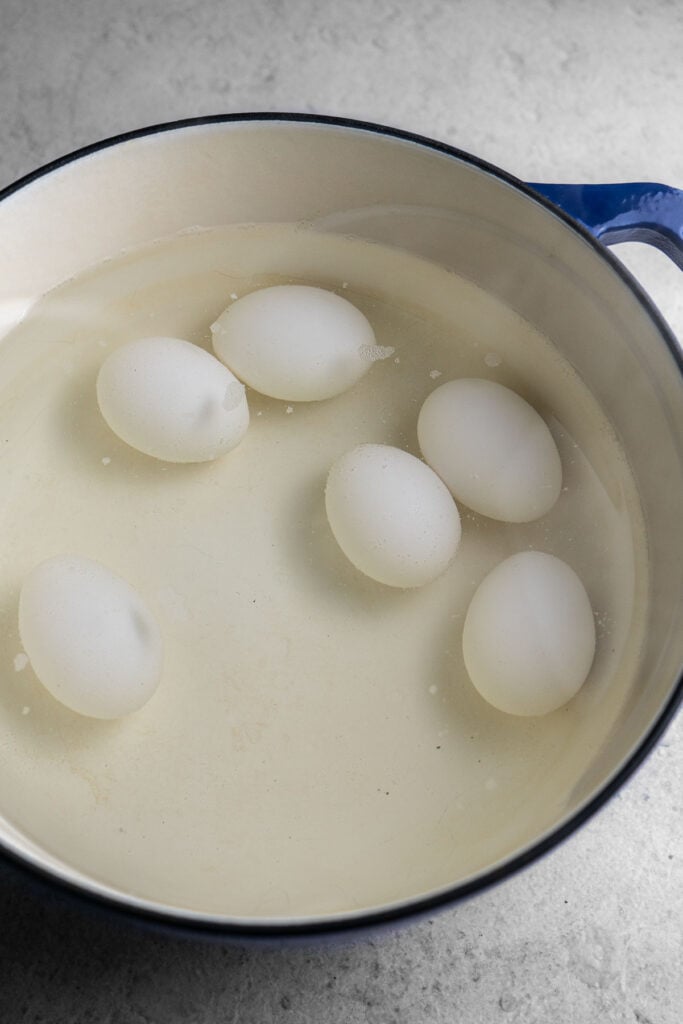 6 Eggs boiling in a large pot.