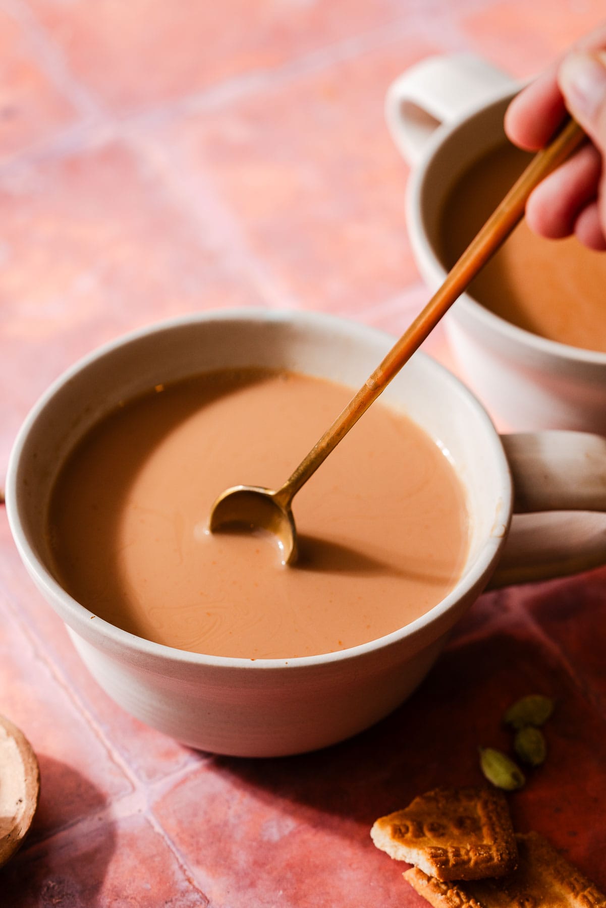 A spoon mixing cardamom chai in a mug.