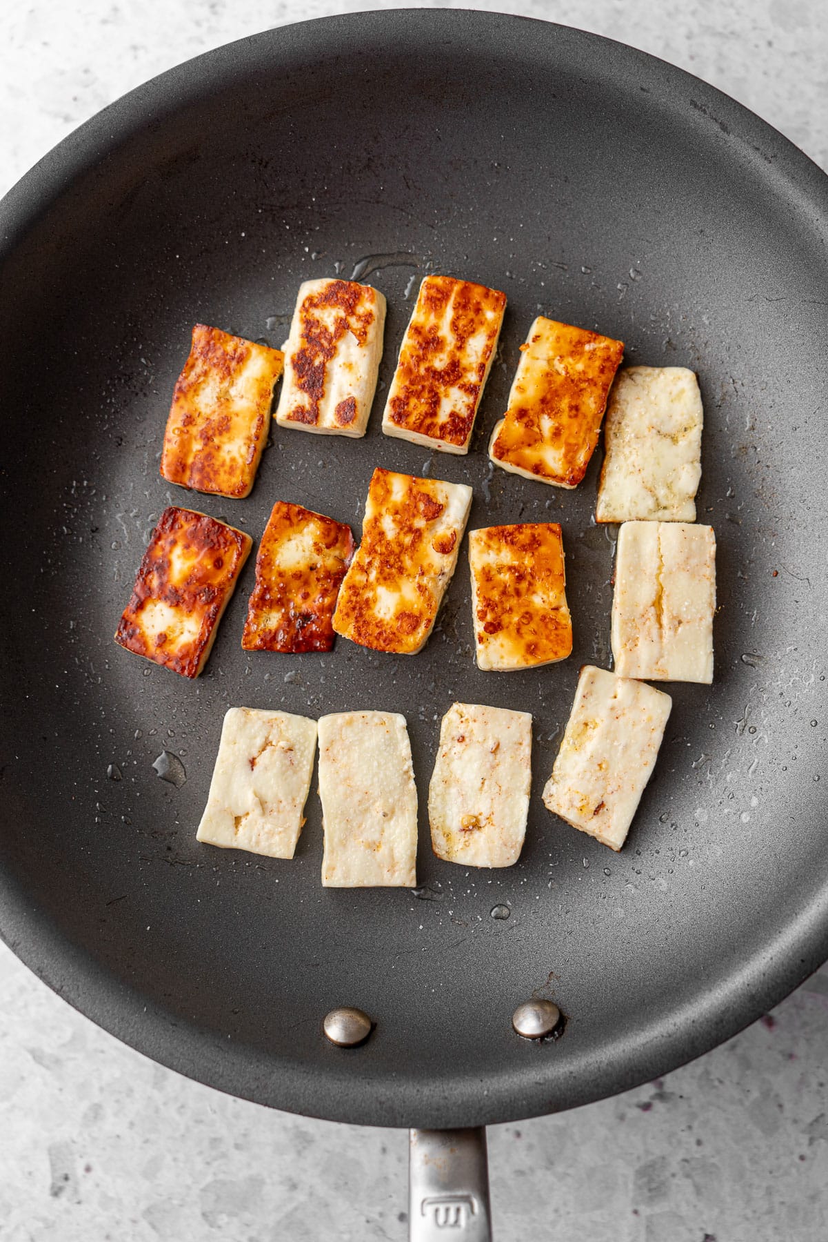 Half fried half unfried paneer in a fry pan.