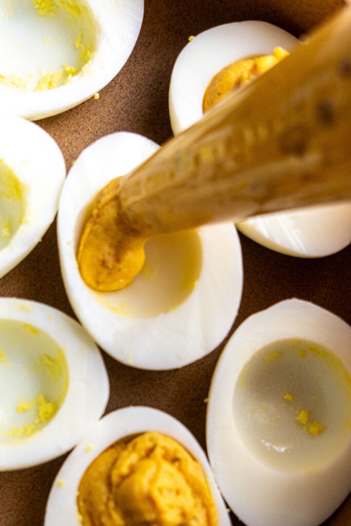 Piping the achaari egg yolk into an egg white.