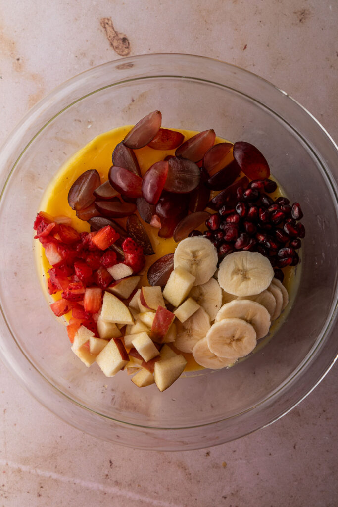 Chopped banana, pomegranate, grapes, apple, strawberries over custard.