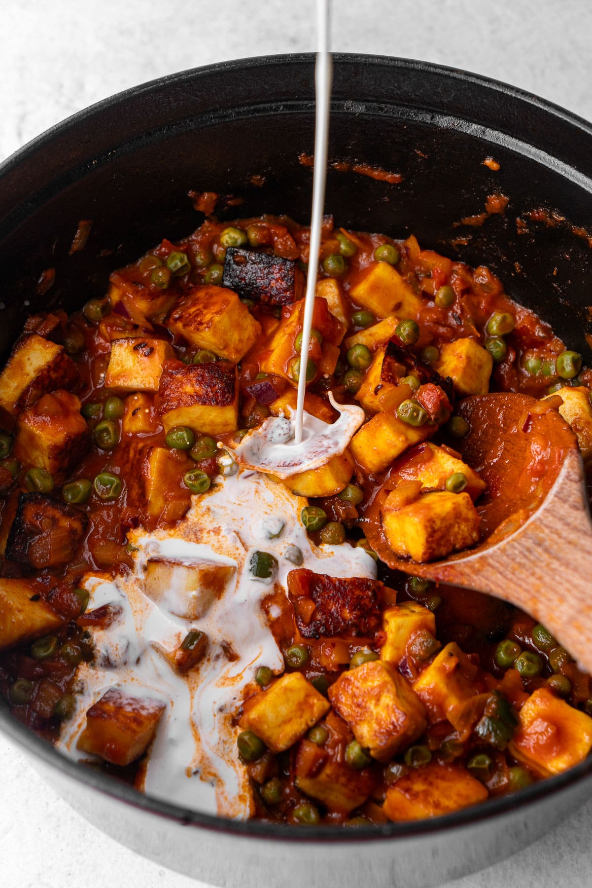 Pouring cream in an oven with mattar paneer.