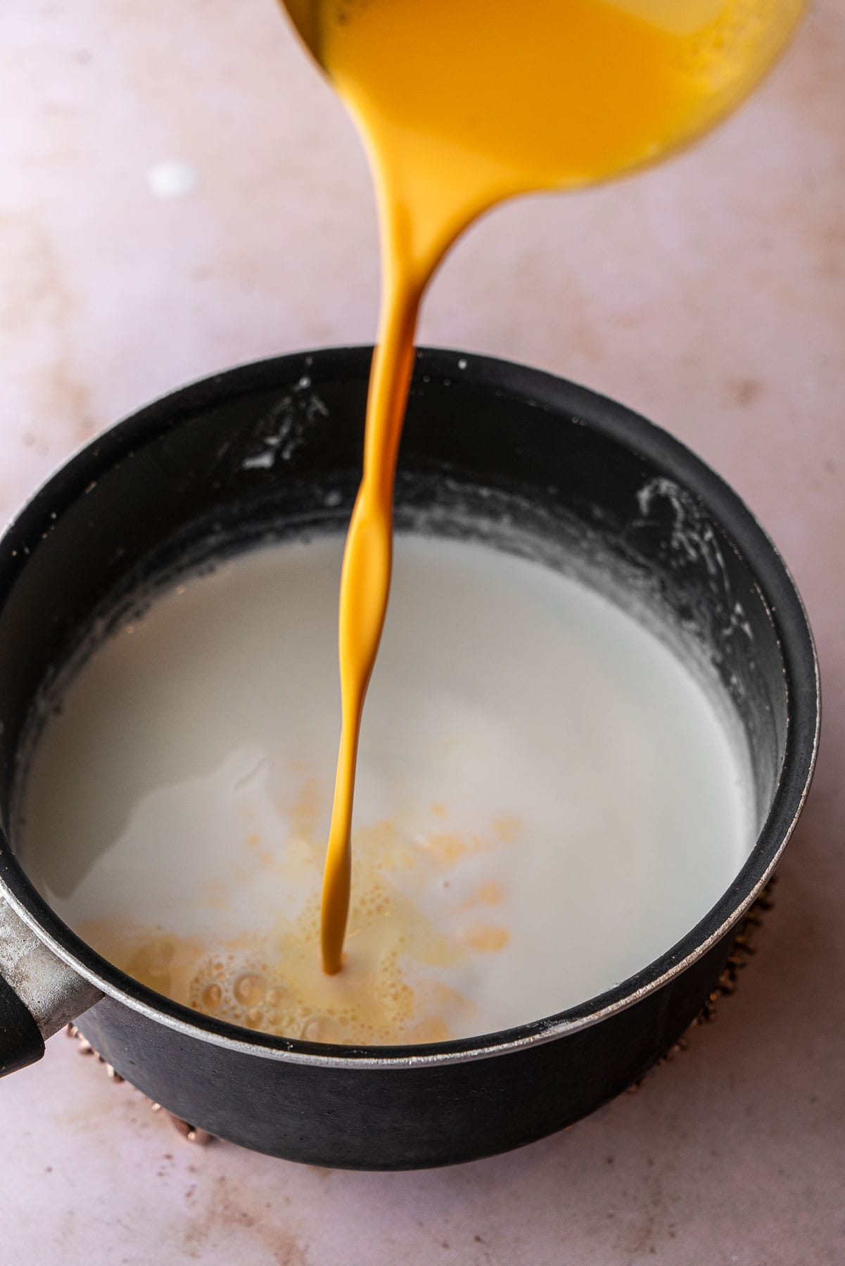 Hydrated custard poured into a pot of milk.