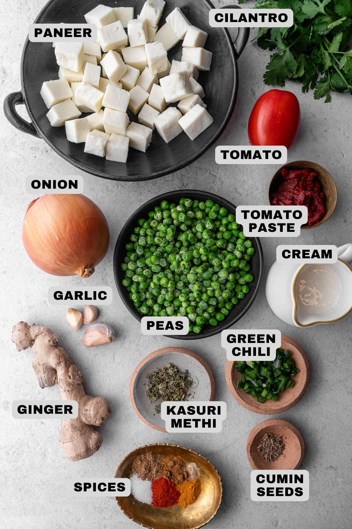 Paneer, cilantro, tomato, onion, tomato paste, cream, peas, garlic, green chili, kasuri methi, ginger, spices, cumin seeds ingredients with labels.