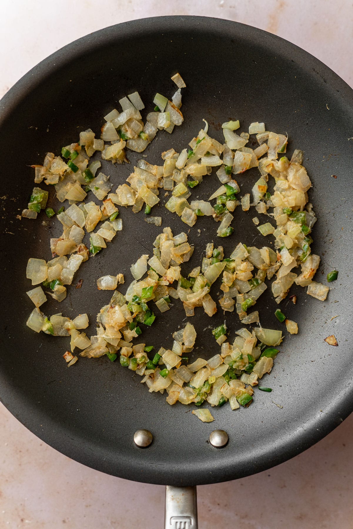 Sauteed translucent onions and green chilis in a nonstick pan.