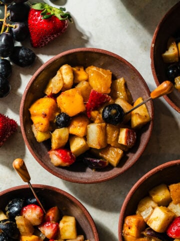 A small dessert bowl of fruit chaat with an appetizer pick.