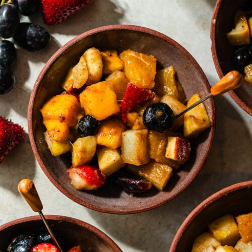 A small dessert bowl of fruit chaat with an appetizer pick.