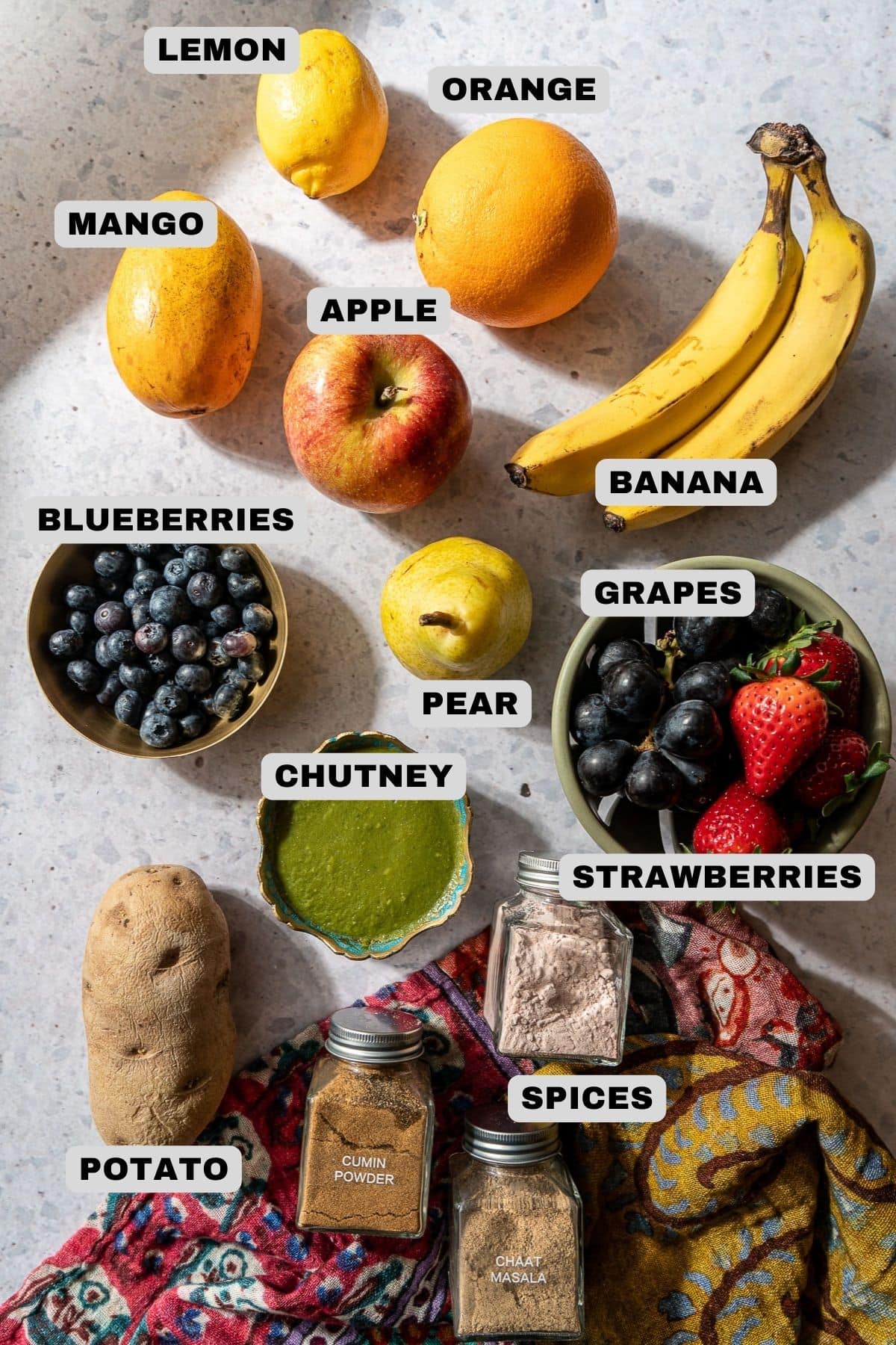 Fruits, chutney, spices, and a potato ingredients with labels.