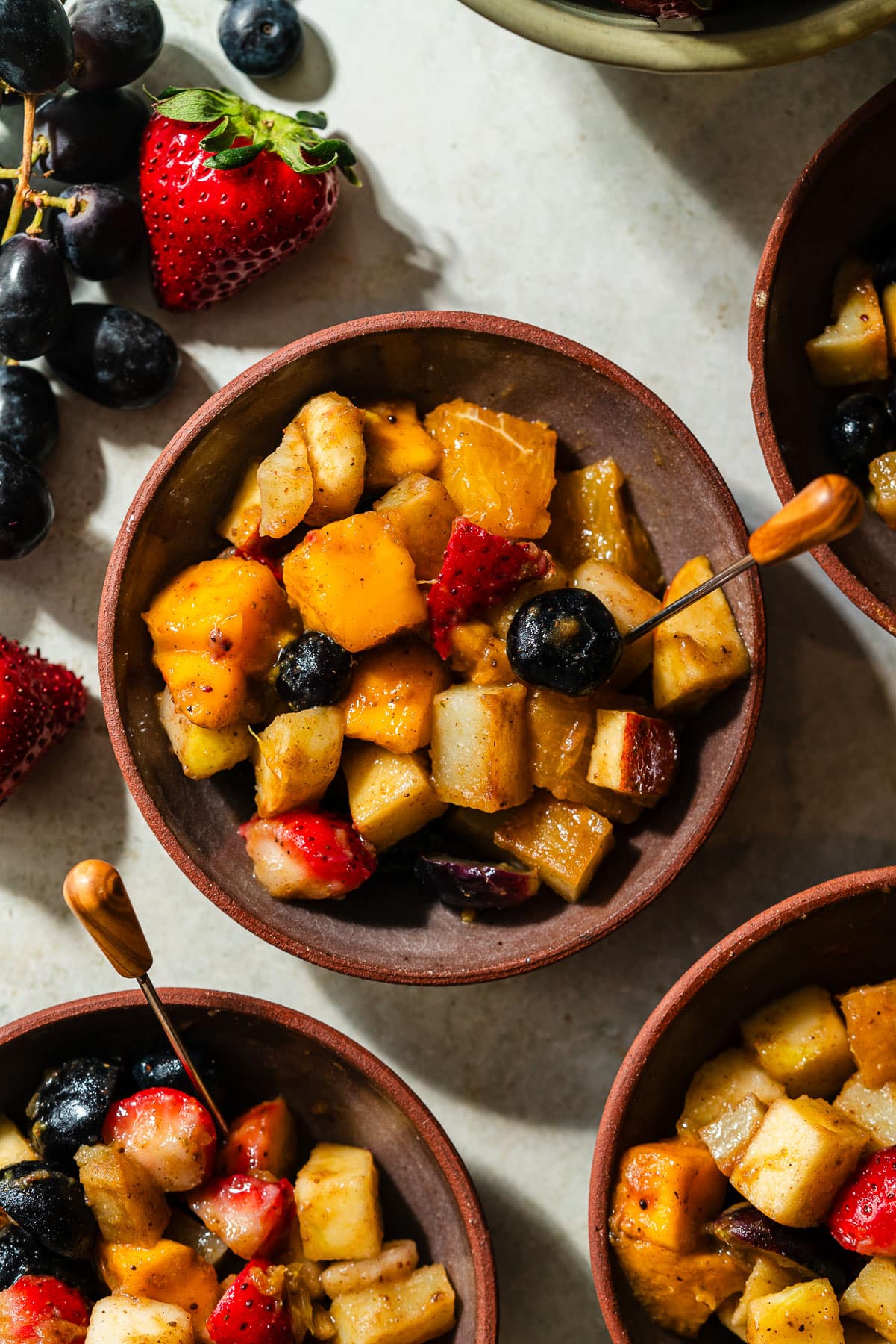 A small dessert bowl of fruit chaat with an appetizer pick.