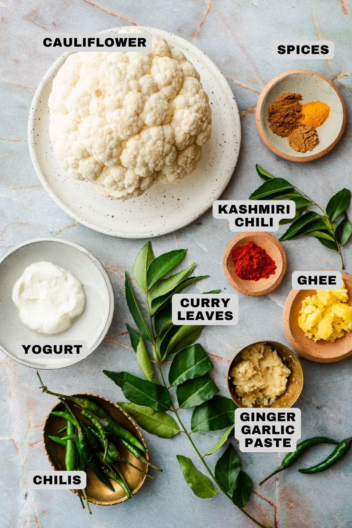Cauliflower, spices, Kashmiri chili, curry leaves, ghee, ginger garlic paste, yogurt, and chilis ingredients with labels.
