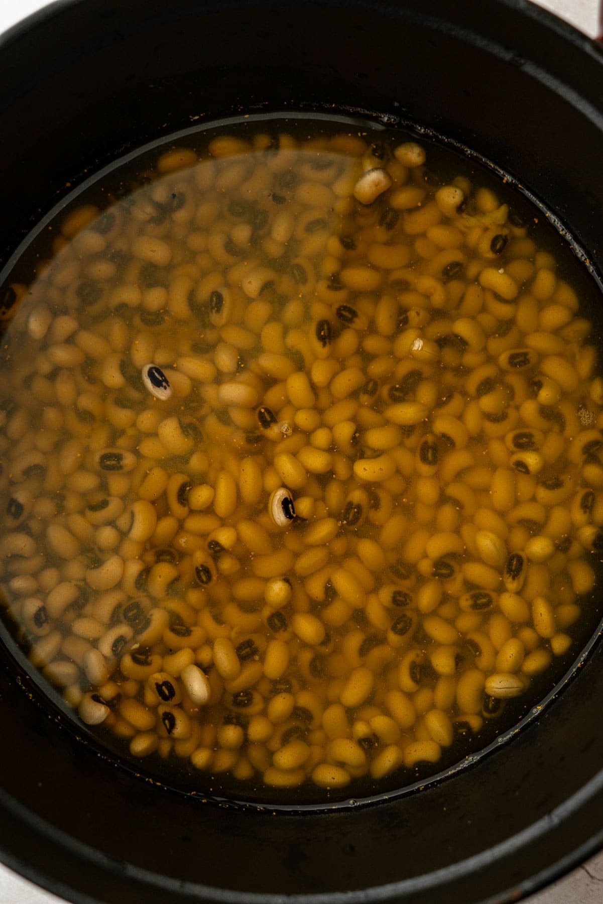 Uncooked black eyed peas in a pot with turmeric and ginger.