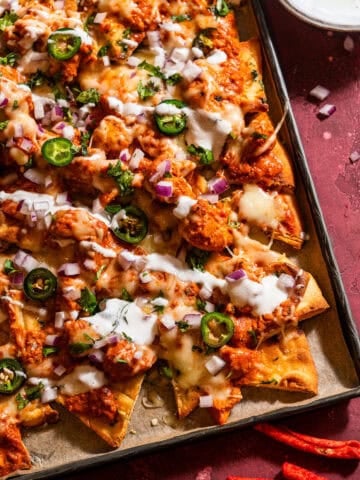 Naan-chos with butter chicken and cheese in a sheet tray.