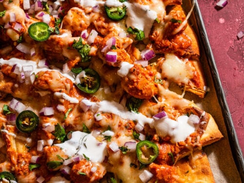 Naan-chos with butter chicken and cheese in a sheet tray.