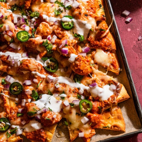 Naan-chos with butter chicken and cheese in a sheet tray.