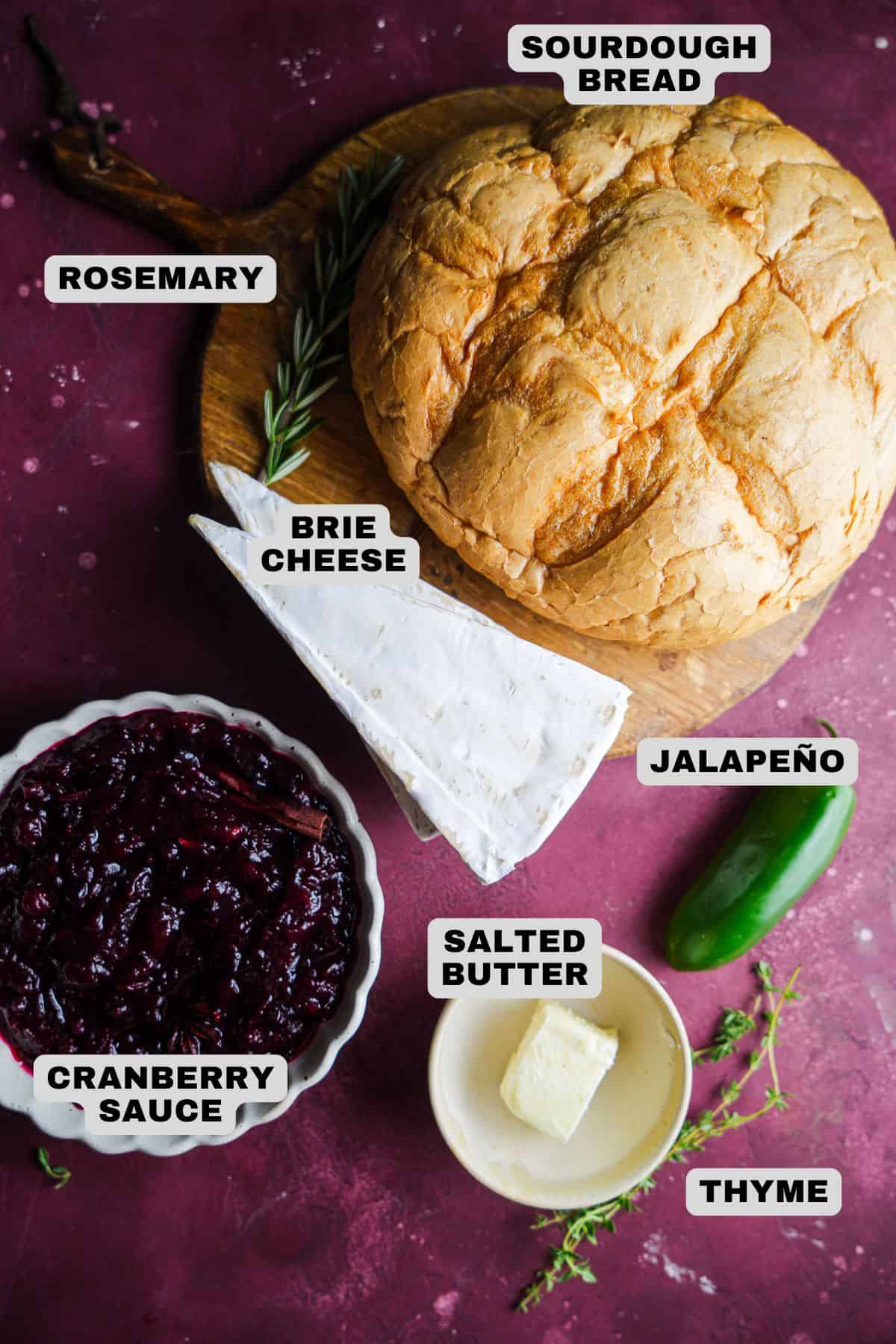 Sourdough bread, rosemary, brie cheese, jalapeno, salted butter, thyme, cranberry sauce ingredients with labels.