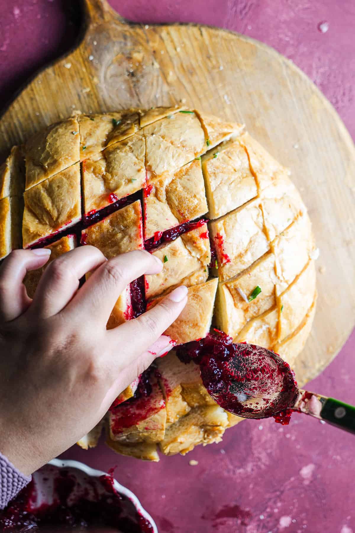 Spooning in cranberry sauce into sliced sourdough.