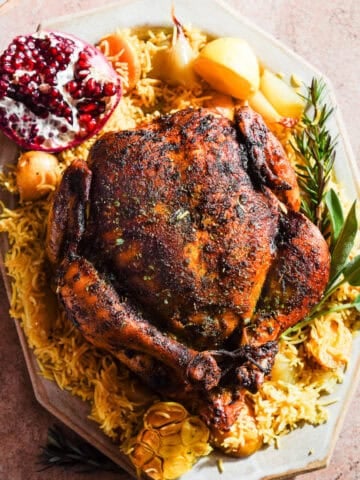 Curried Chicken on top of a bed of rice with potatoes and herbs on a platter.