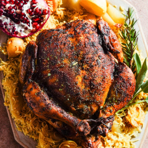 Curried Chicken on top of a bed of rice with potatoes and herbs on a platter.