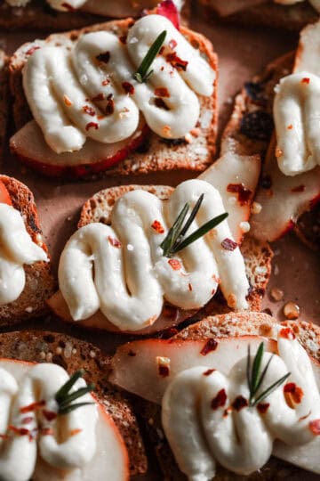 Pear and whipped brie on crackers in a platter.