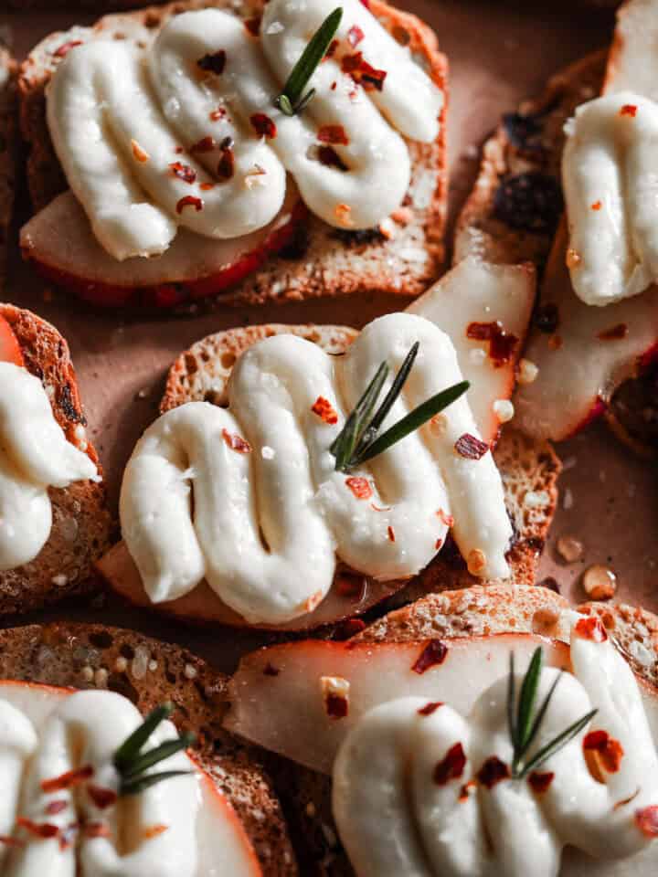 Pear and whipped brie on crackers in a platter.