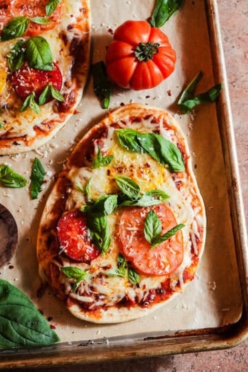 Cheesy naan pizza topped with basil and heirloom tomatoes.