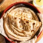 A stack of roti and folded roti in a tortilla warmer.