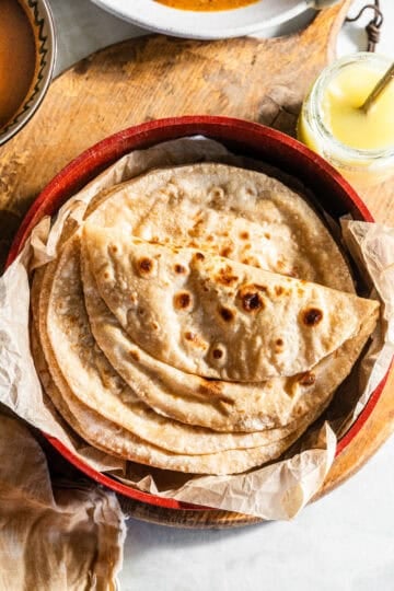 A stack of roti and folded roti in a tortilla warmer.