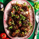 Roasted stuffed eggplant in a platter with fresh tomatoes, rice, and dal.