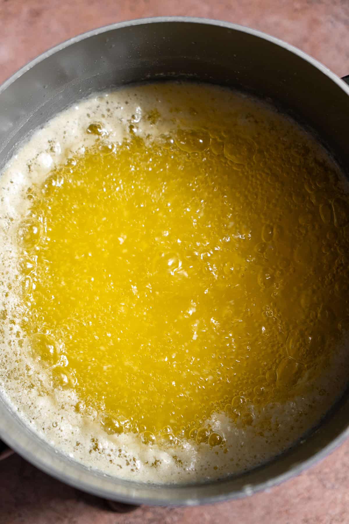 Cloudy melted butter in a pot with foam on the sides.