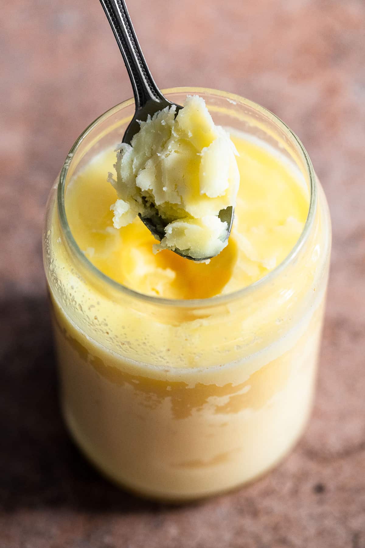 Solidified ghee with a spoon lifting some up.
