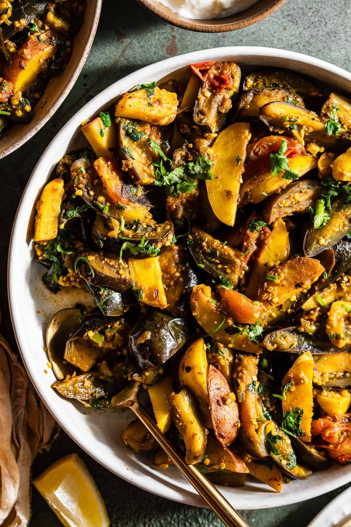 A bowl of food with potatoes, eggplant and tomatoes.