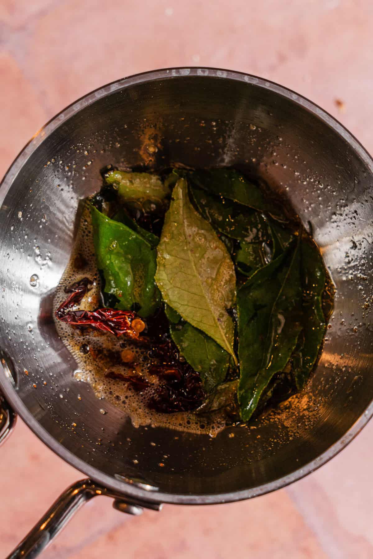 A tadka pan with tempered spices and curry leaves in ghee.