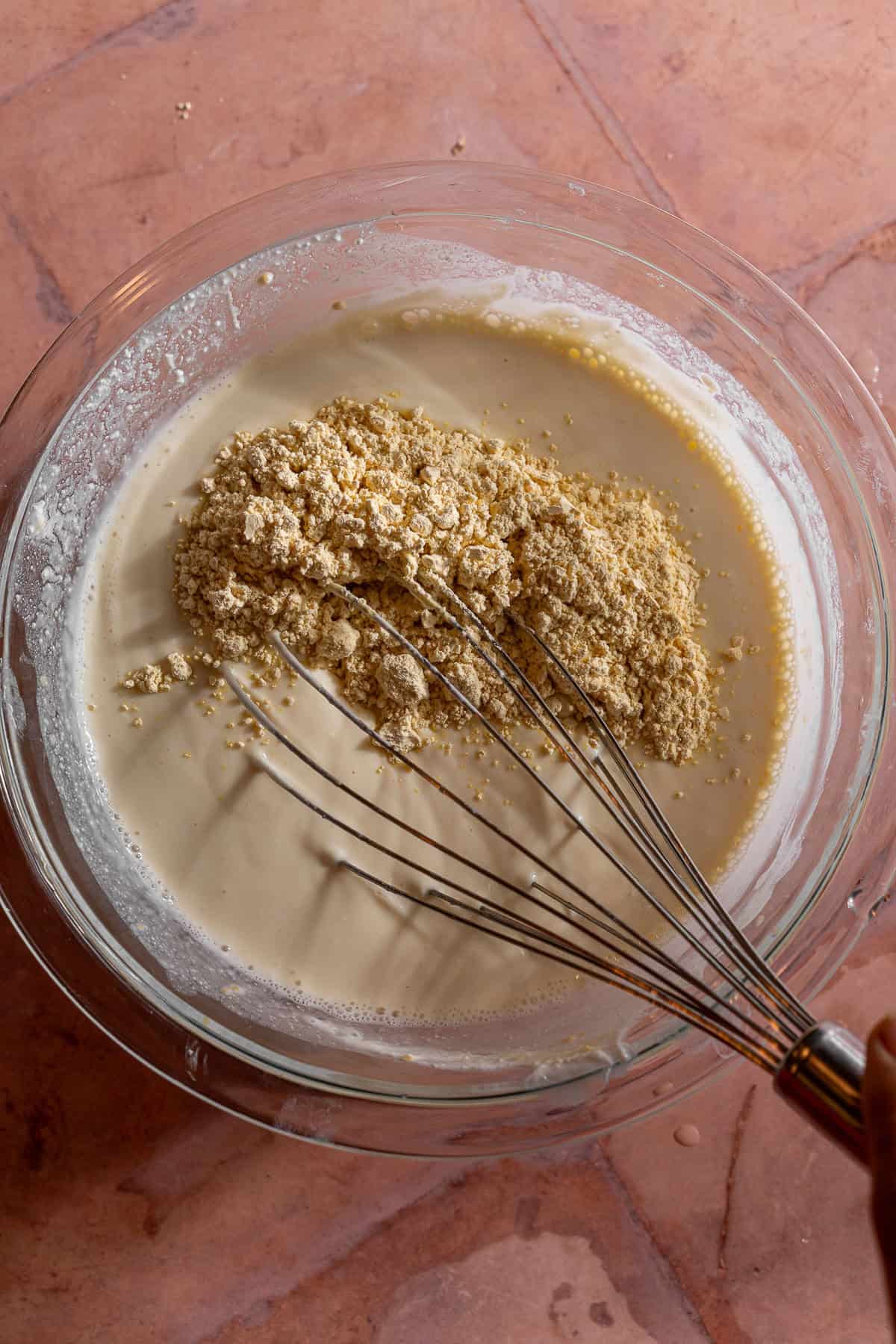 Besan is whisked into a bowl full of yogurt thinned with water.
