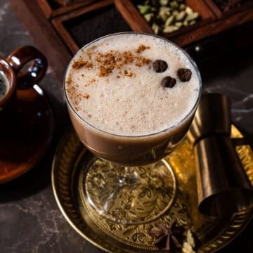 A chai espresso martini in a plate with a chai spice box.