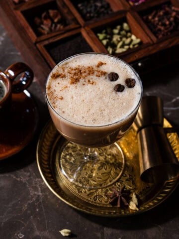 A chai espresso martini in a plate with a chai spice box.