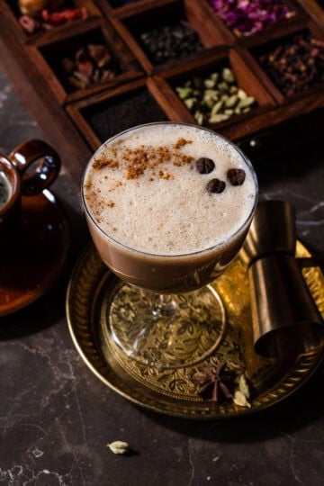 A chai espresso martini in a plate with a chai spice box.