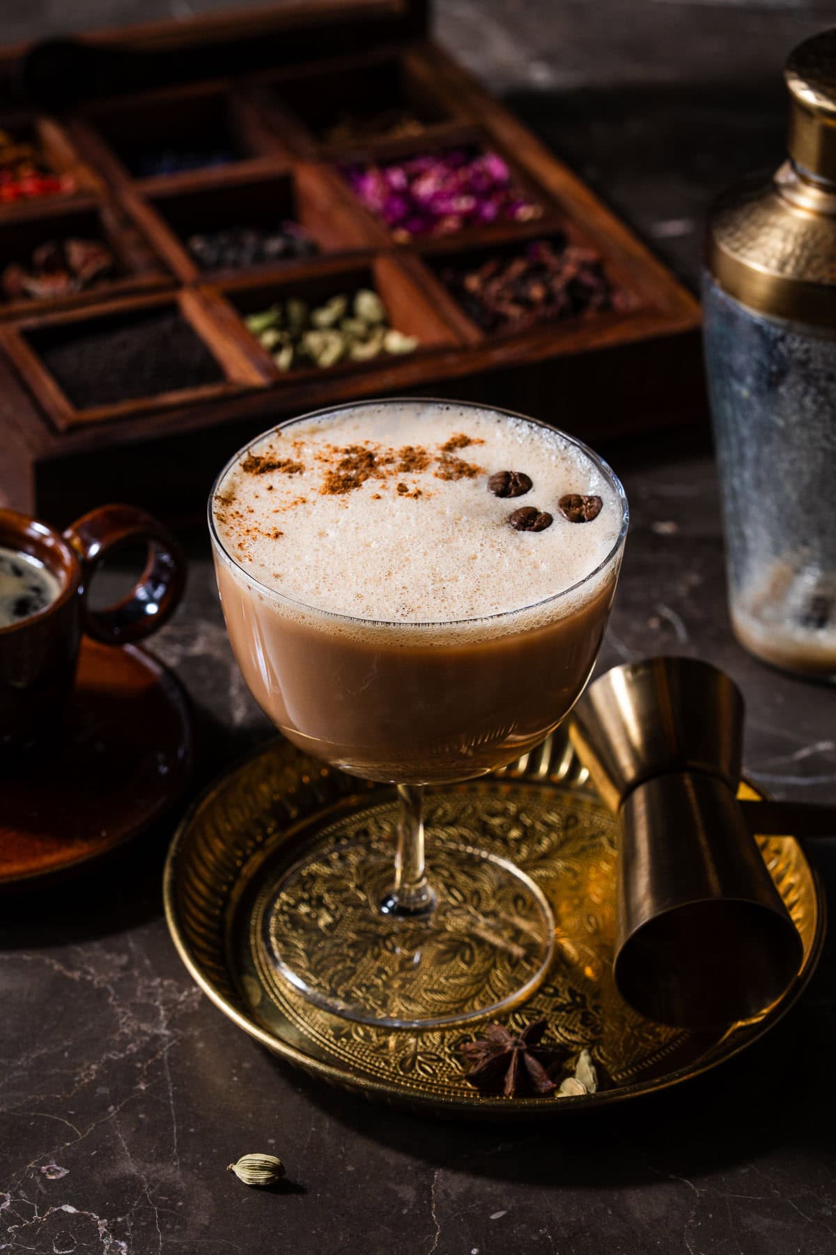 A chai espresso martini in a plate with a chai spice box.