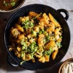 Aloo gobi with paratha, dahi, and rajma in separate bowls and plates.