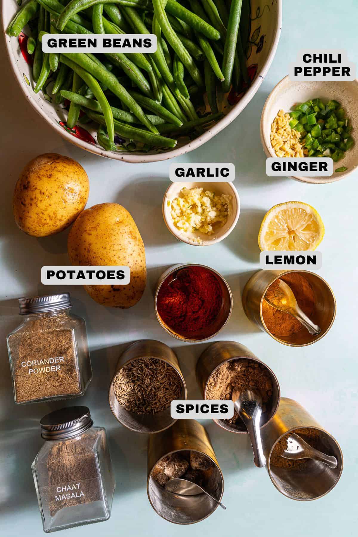 Green beans, chili pepper, ginger, garlic, potatoes, lemon and spices ingredients with labels.