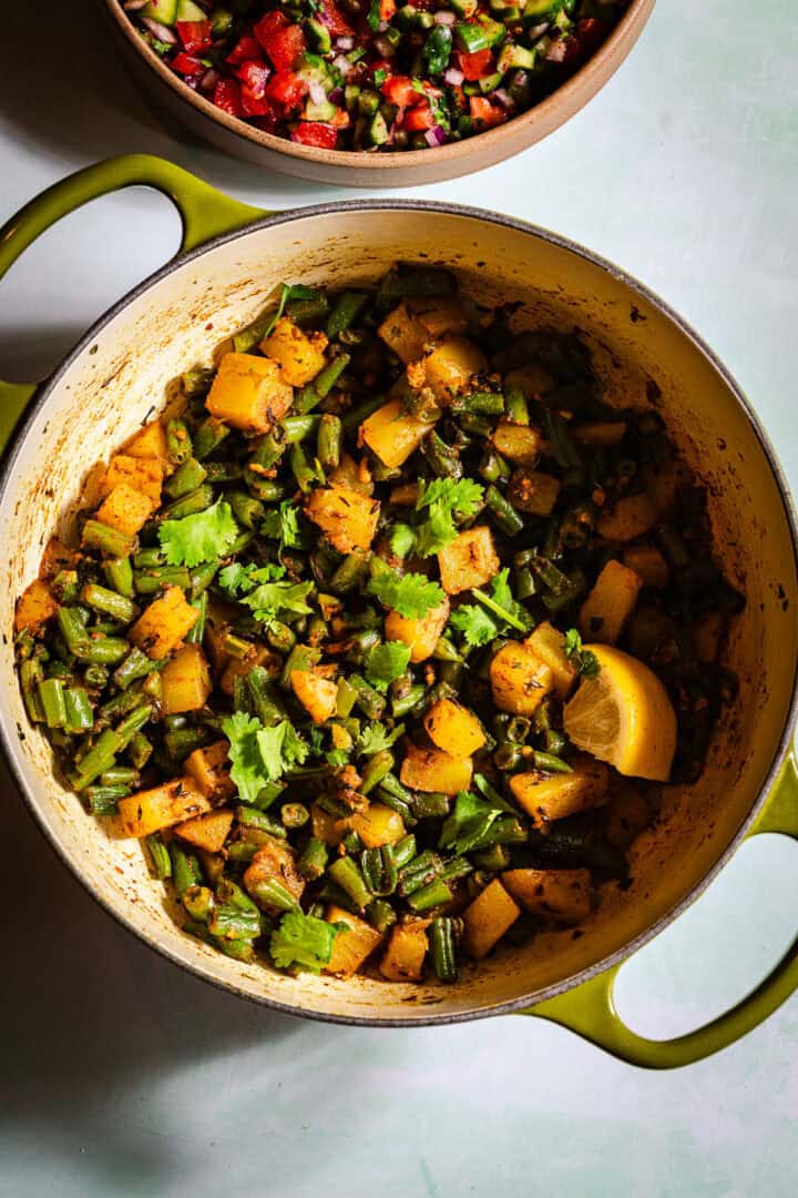 Green beans aloo sabzi in a dutch oven with a side of kachumber salad.