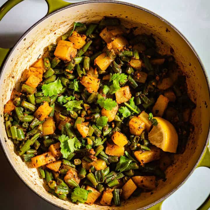 Green beans aloo sabzi in a dutch oven with a side of kachumber salad.
