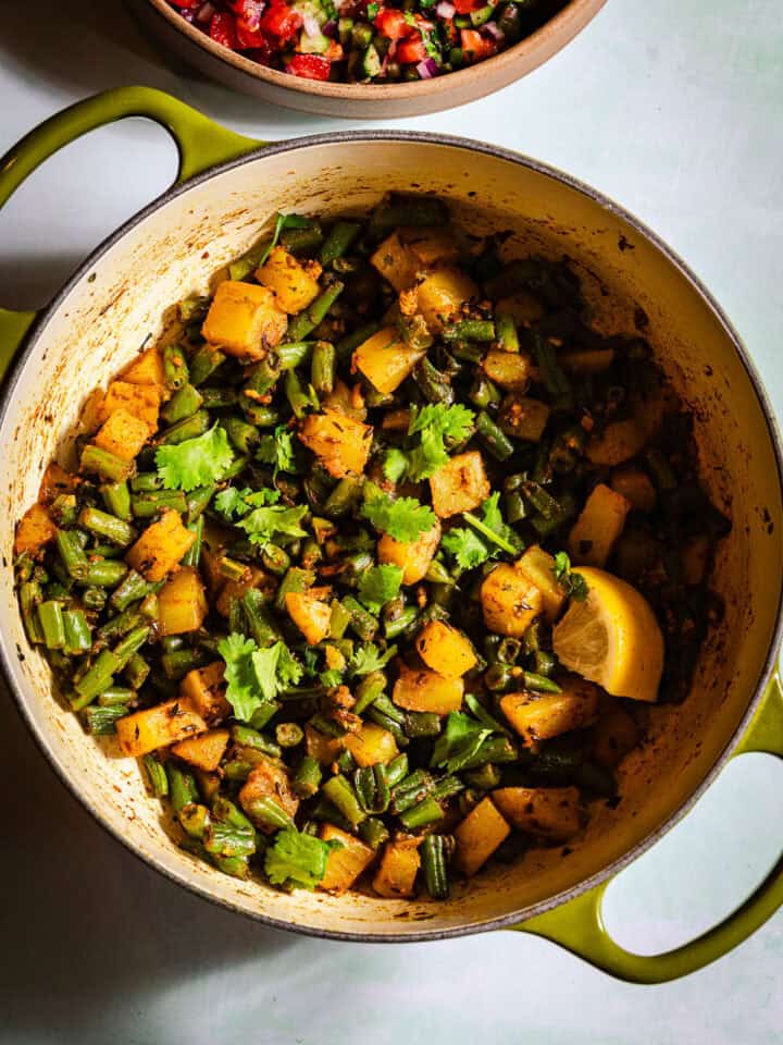 Green beans aloo sabzi in a dutch oven with a side of kachumber salad.