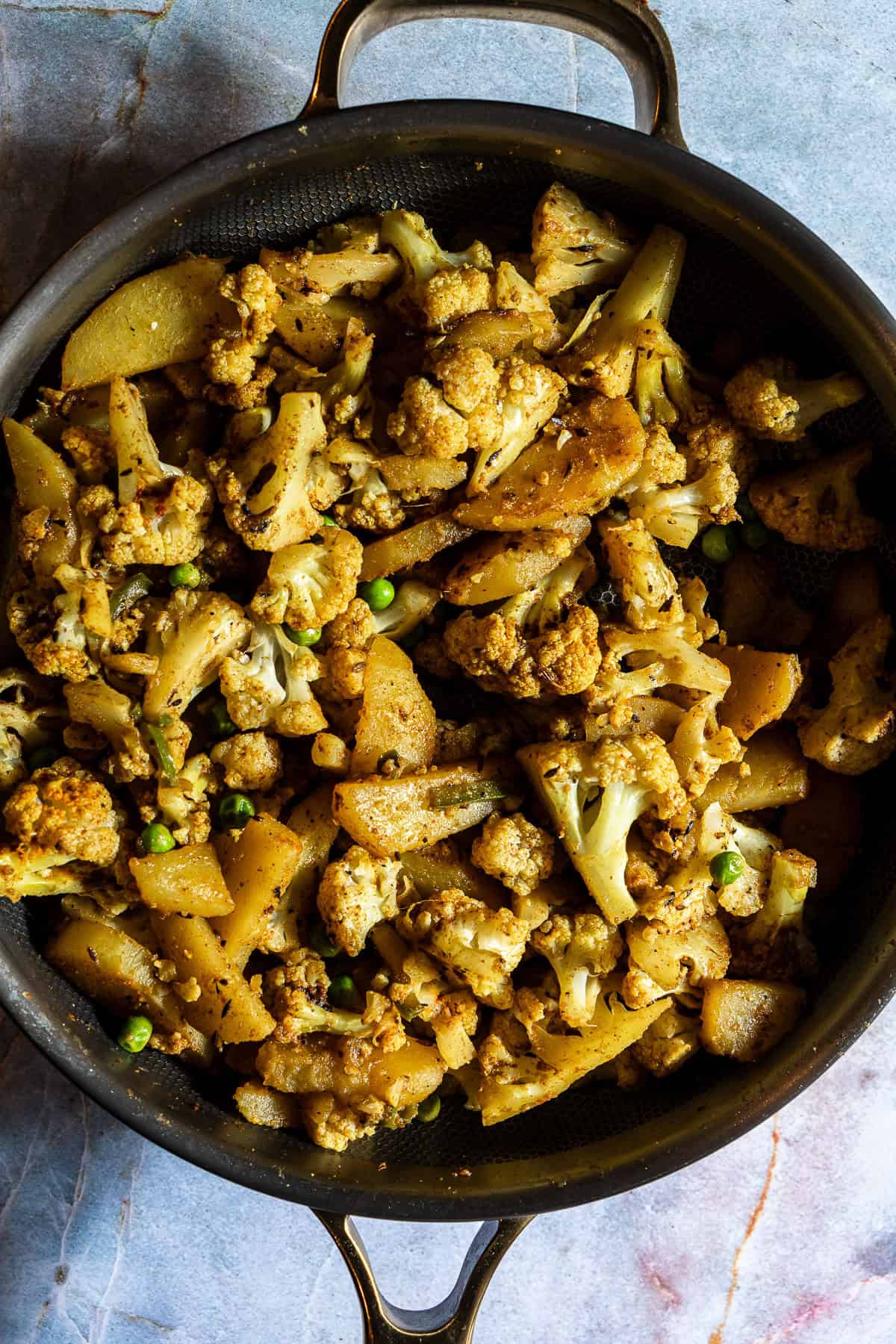 Sauteed potatoes, peas, and cauliflower with spices.