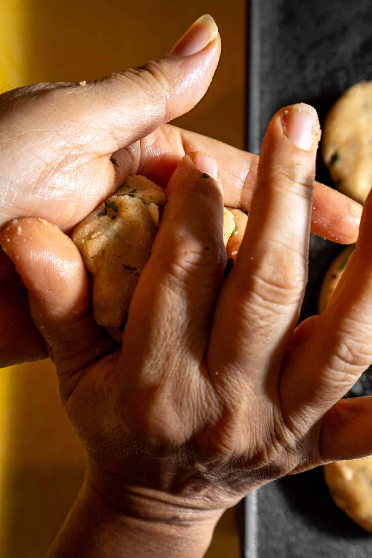 Hands squeezing a small amount of mashed potato into a patty.