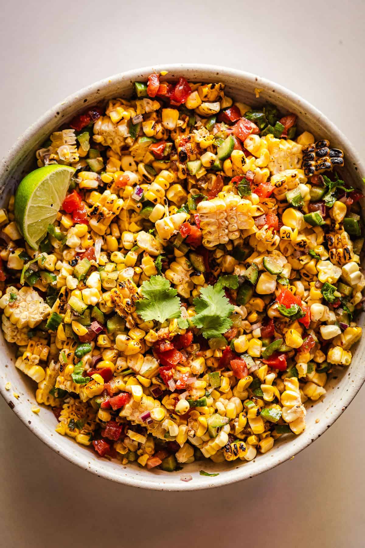 Indian grilled corn salad in a bowl with a lime wedge.