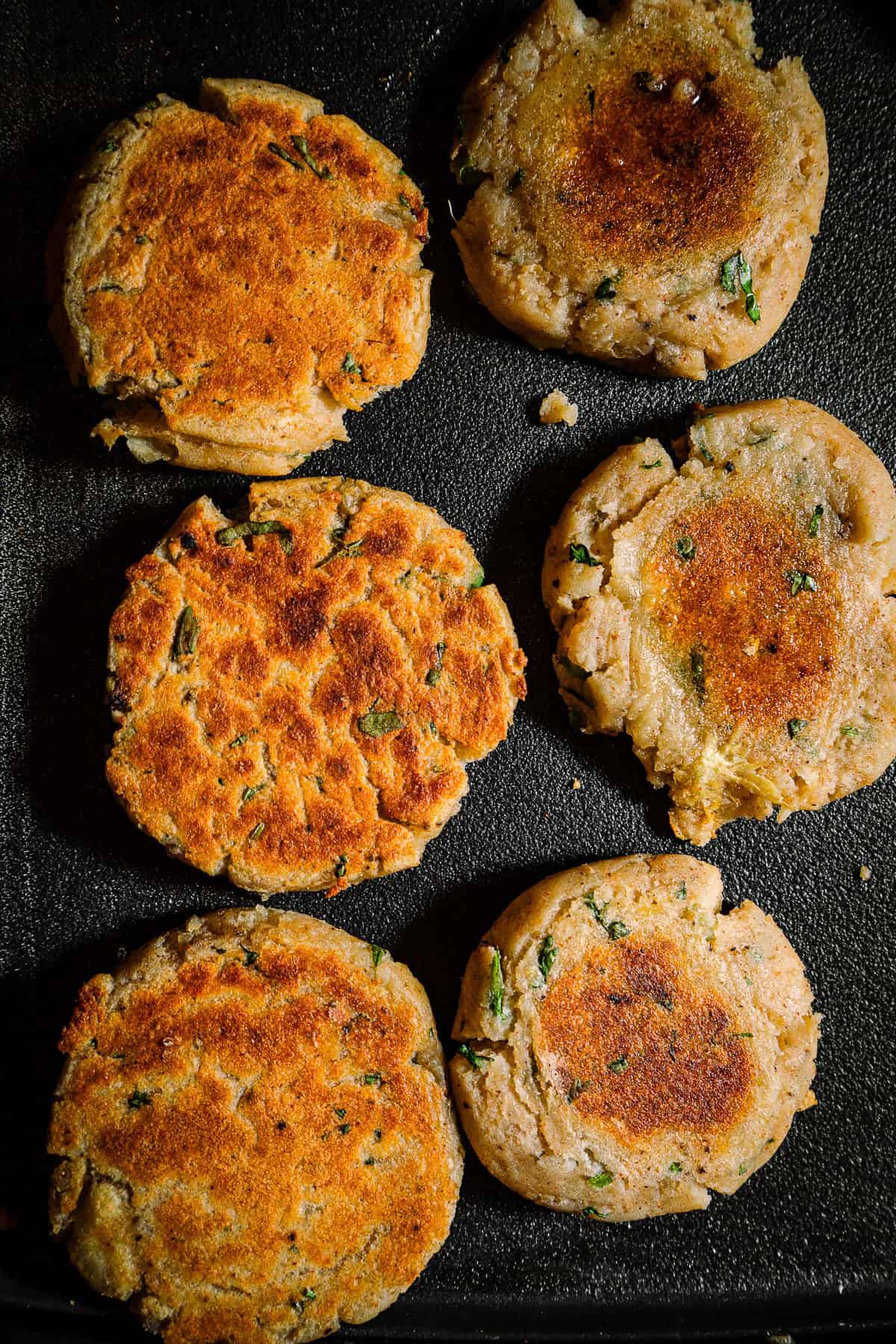 Par cooked aloo tikkis on a griddle.