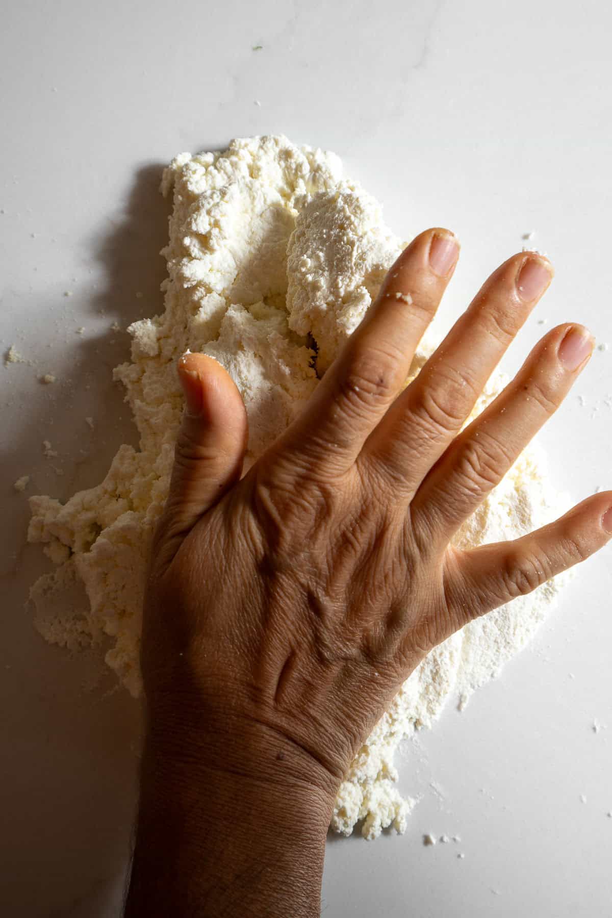 A hand kneading a ball of chenna.